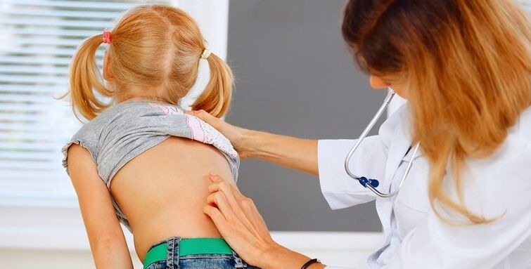 лекар који прегледава леђа детета због болова у доњем делу леђа
